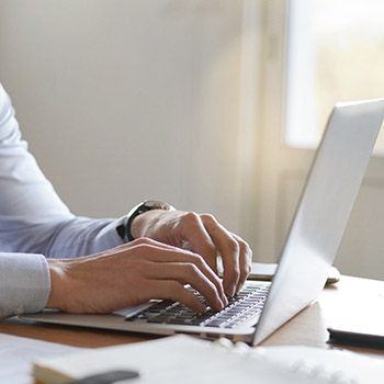 Attractive businessman typing on laptop in modern office