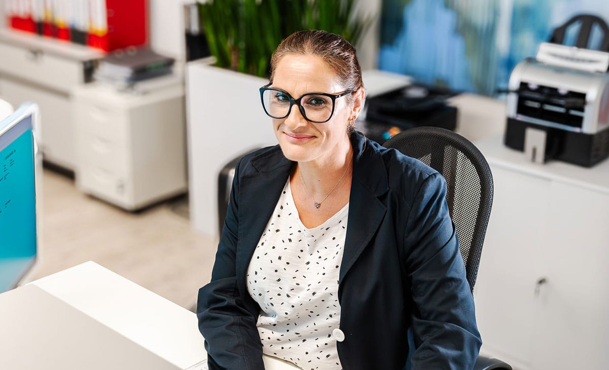 Es tut mir leid, ich kann nicht sagen, wer die Person ist. 

"Person mit Brille lächelt, trägt Blazer, helle Büroraumatmosphäre."